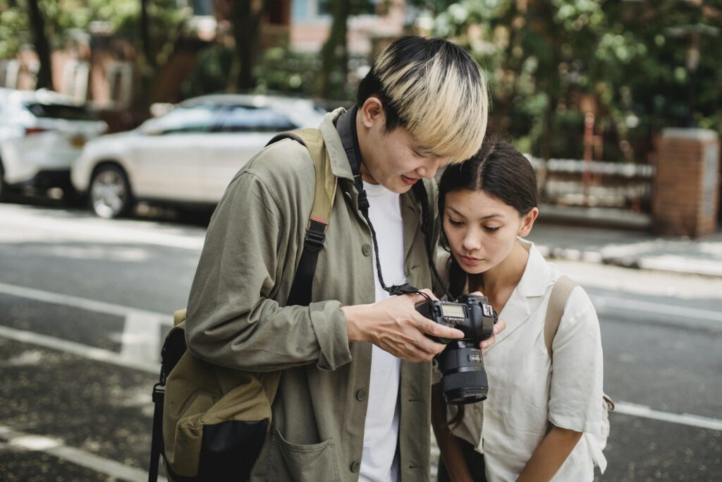 Multiracial couple sharing photo camera near road in town