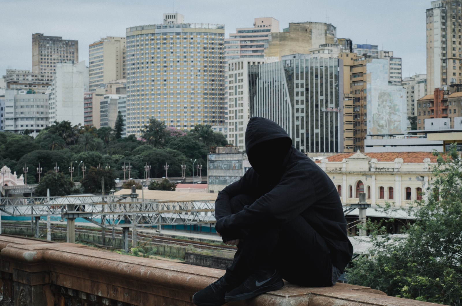 man wearing hooded jacket sitting on beige concrete