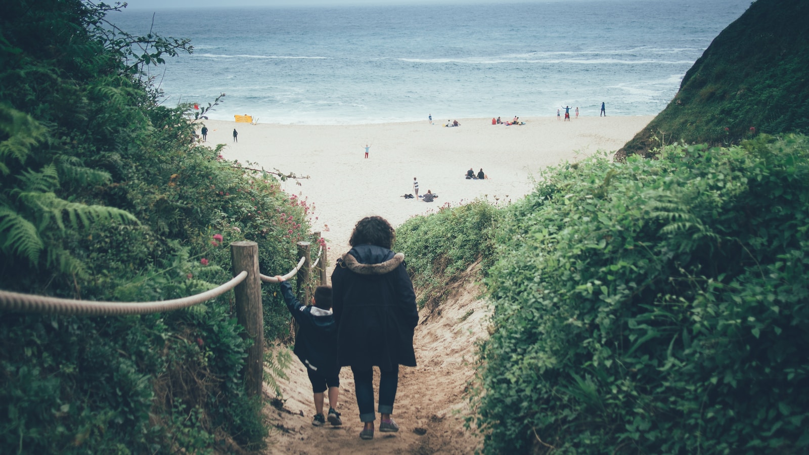 woman in black dress standing on beach during daytime