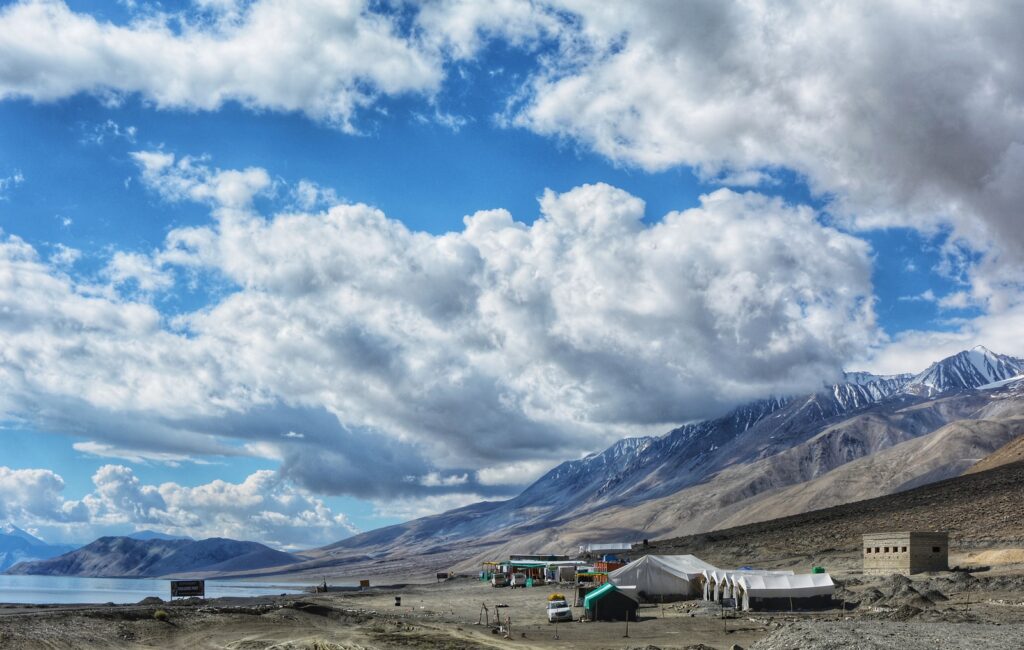 white and black house on brown field under white clouds and blue sky during daytime