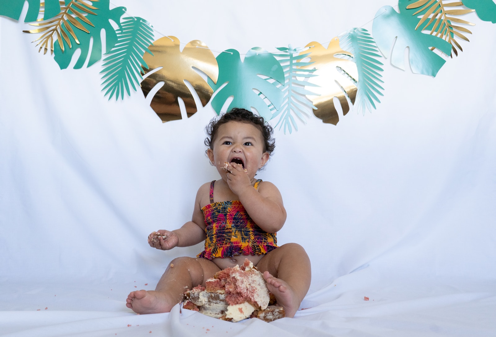 baby in red and white tank top sitting on white textile