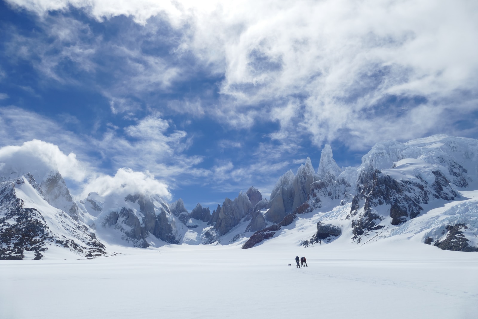 two persons standing near mountain during winter season