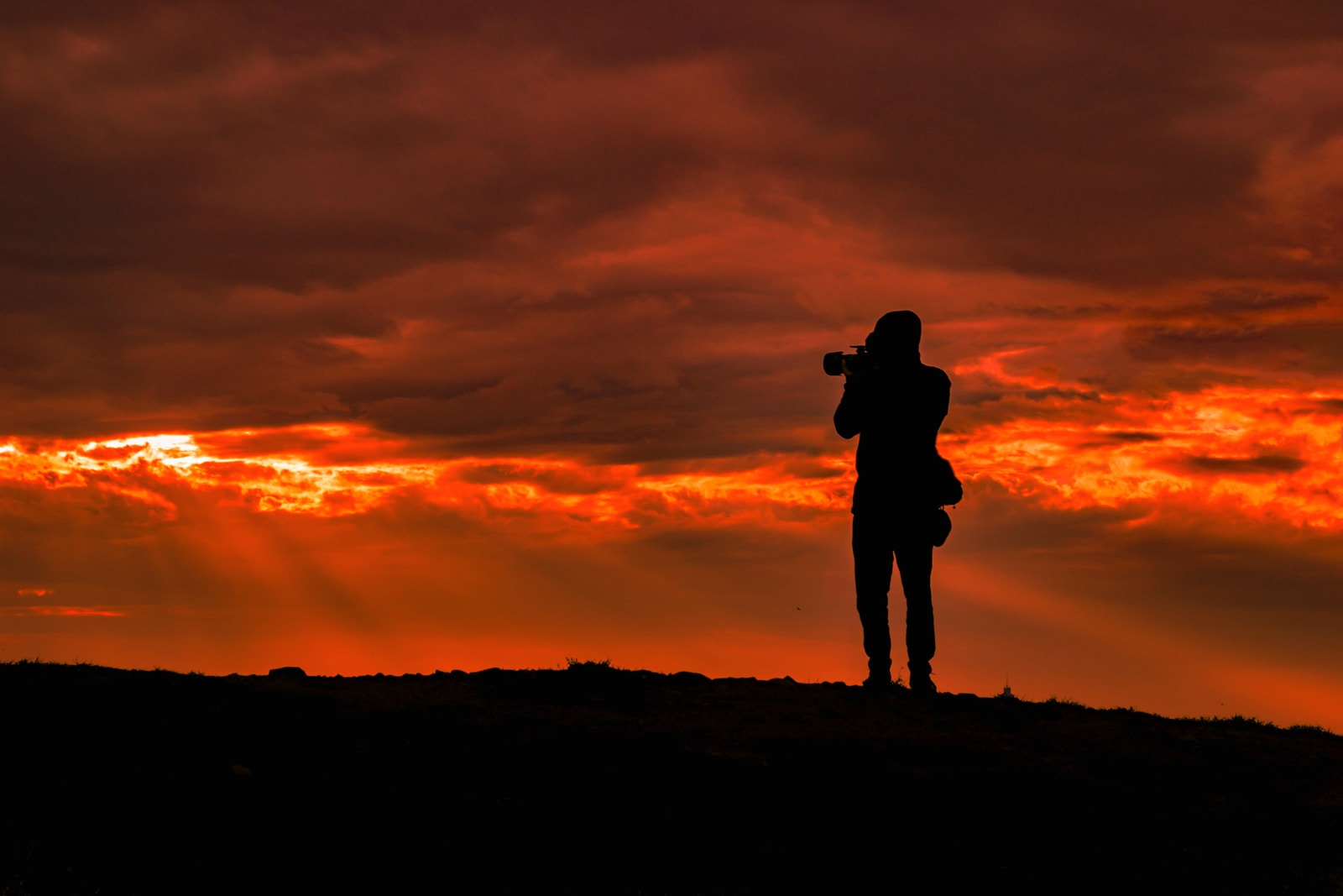 silhouette of man standing on hill during sunset