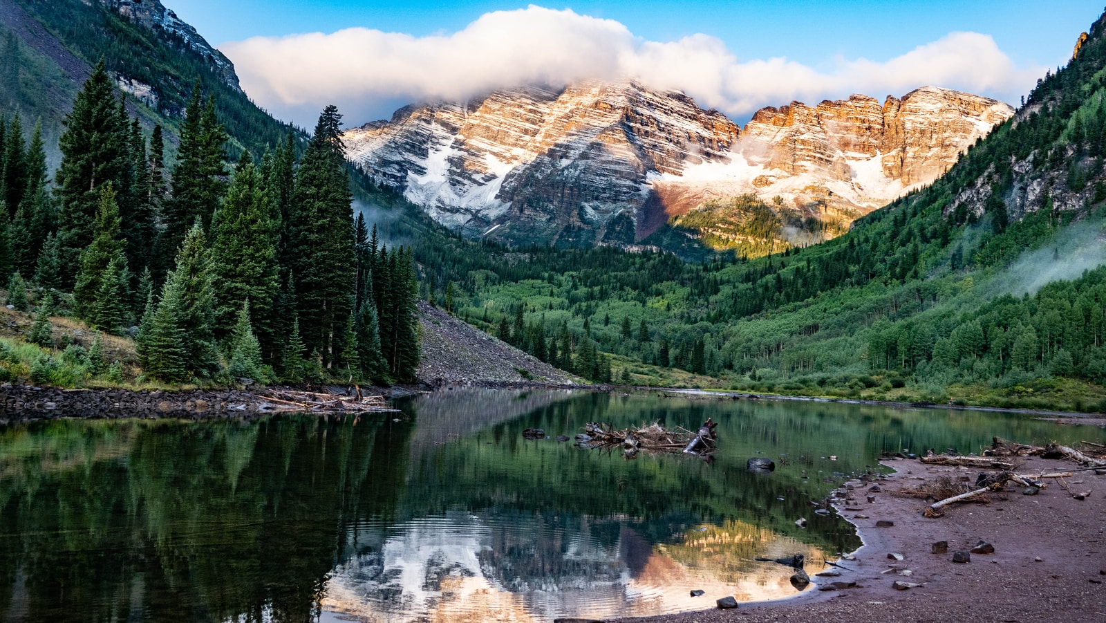 green pine trees near lake and snow covered mountain during daytime