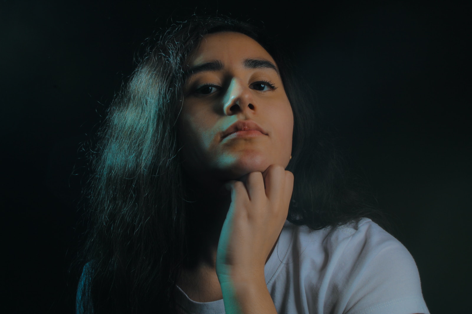 woman wearing white crew-neck t-shirt putting left hand on her chin