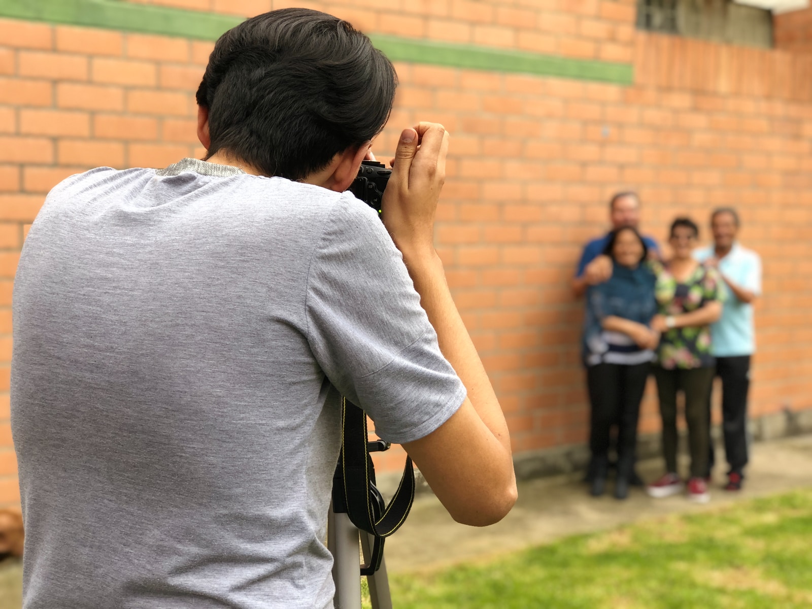 man taking picture to four people standing beside wall